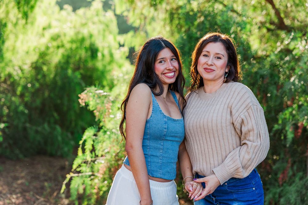 Three people pose together outdoors against a bright green natural background.