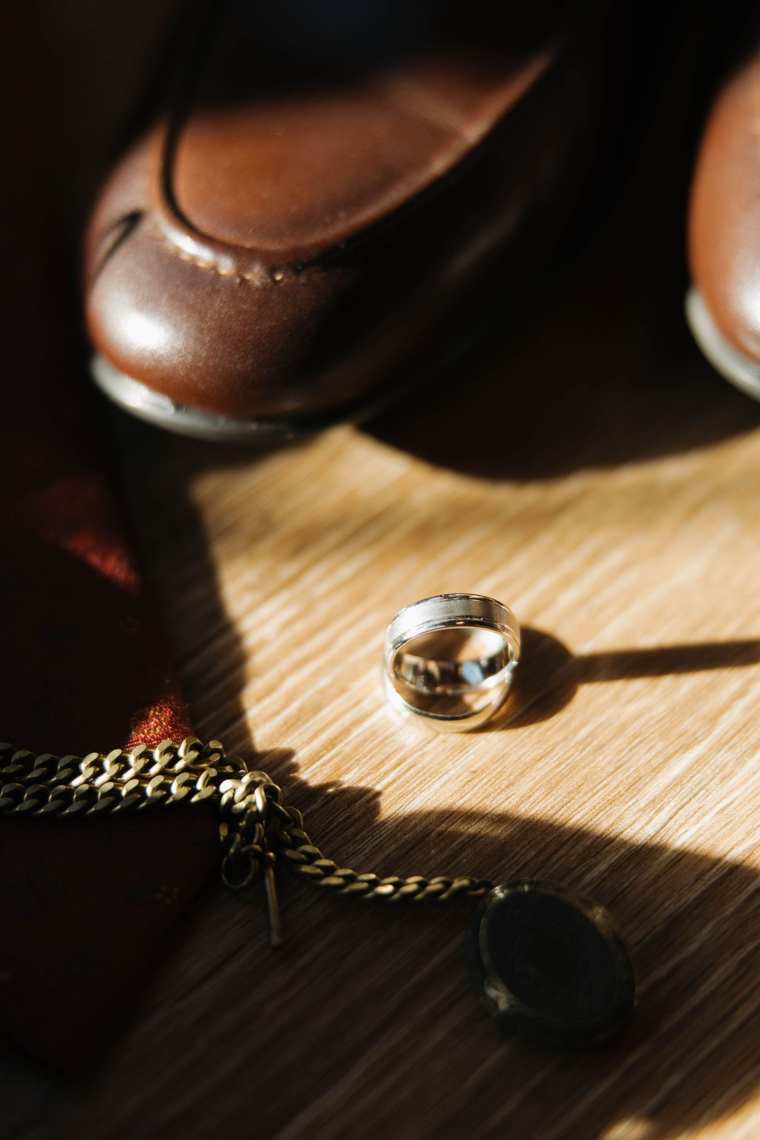 Macro shot of vintage coins and chain links casting dramatic shadows on a wooden surface in natural light.