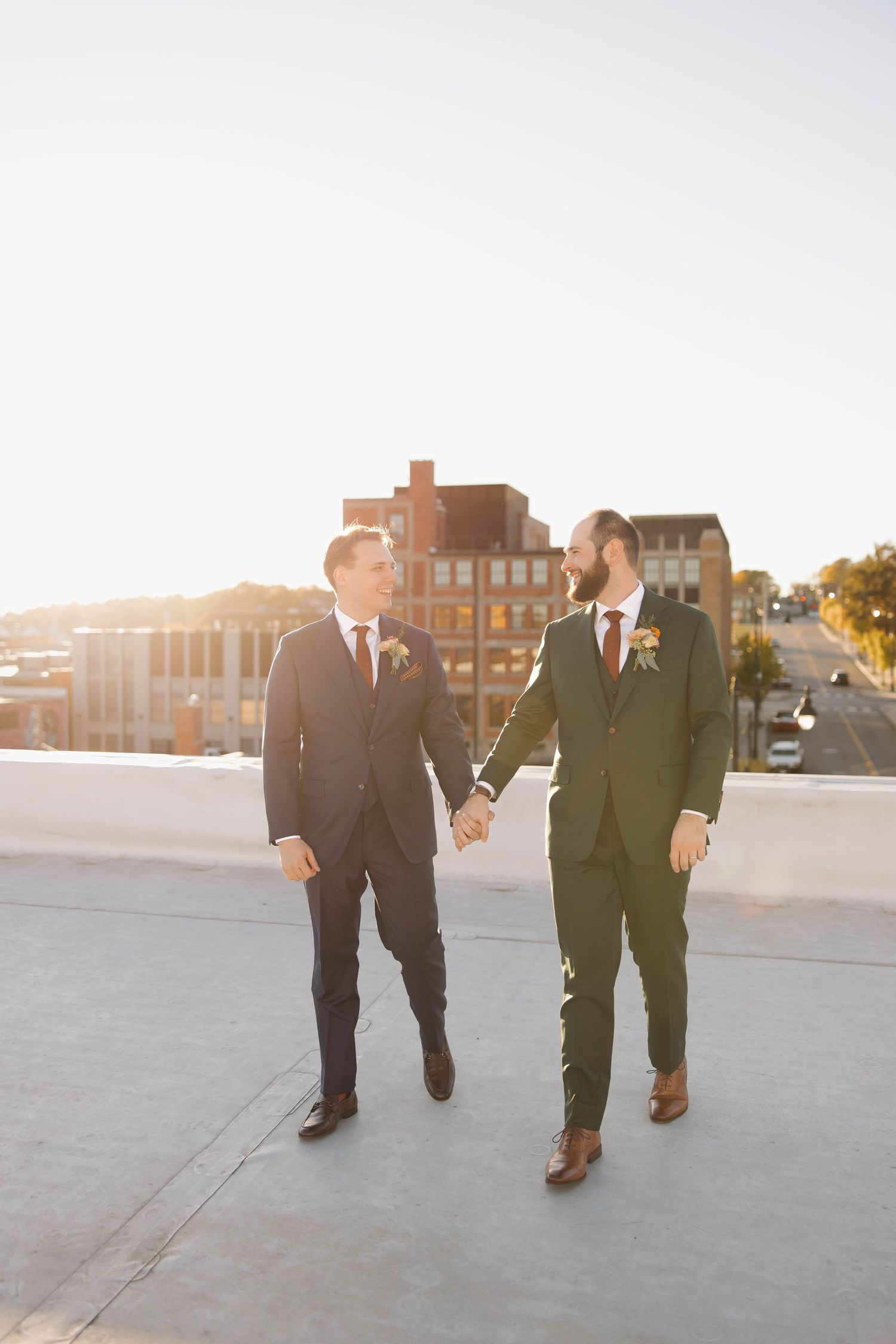 Groomsmen walk together on a sunlit plaza during golden hour at sunset.