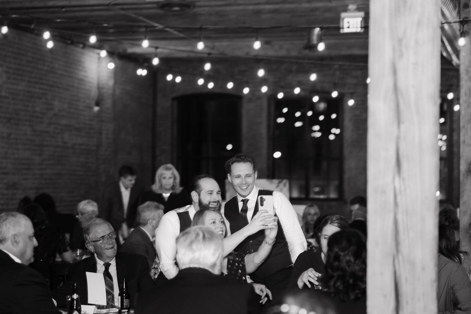 Wedding reception venue with exposed brick walls and string lights creating an intimate atmosphere.