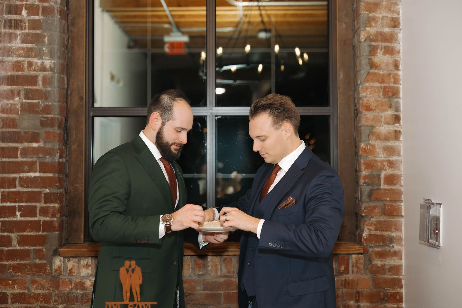 Two people interact in a rustic brick-walled venue with modern lighting fixtures.