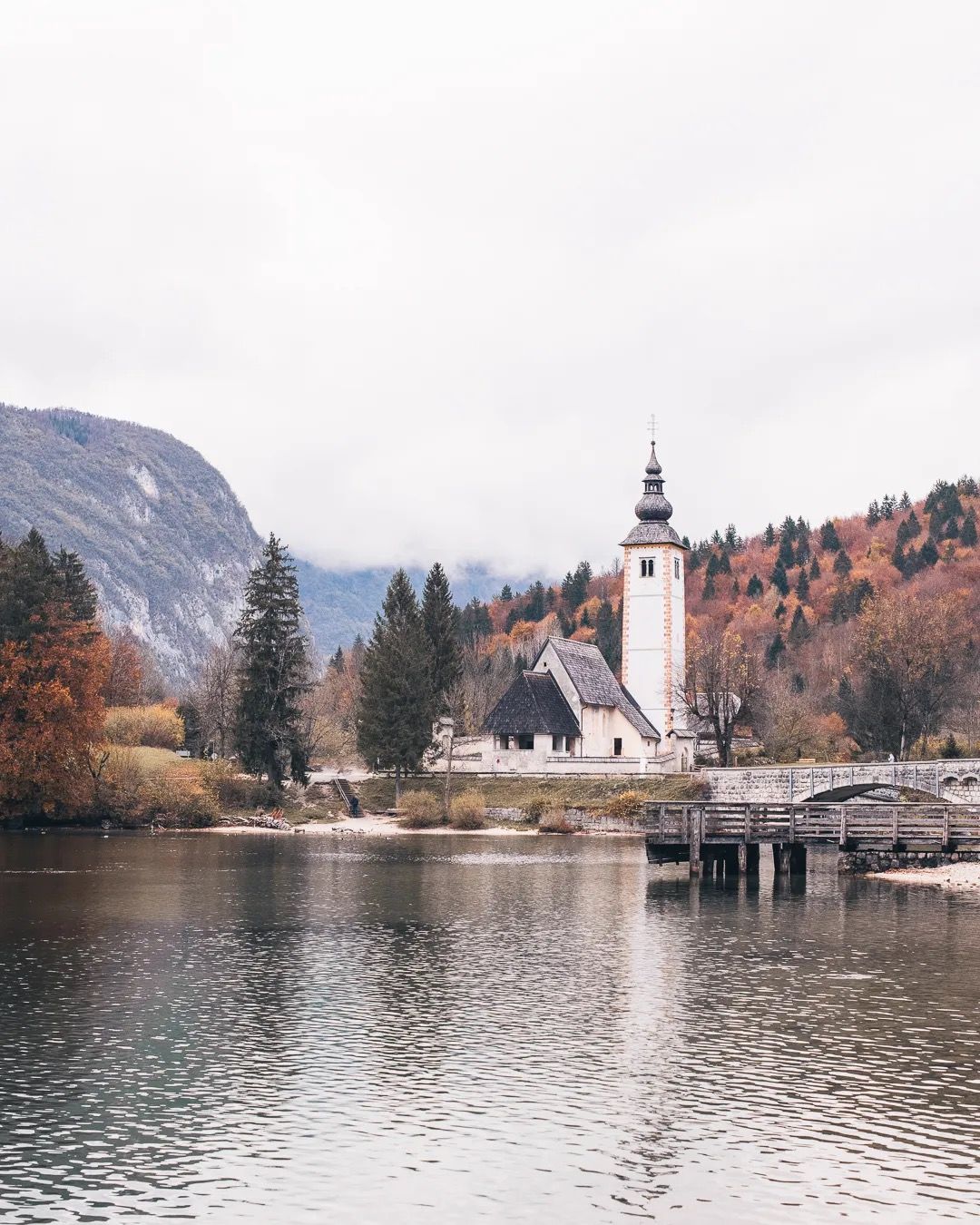 Church on the edge of a lake with mountains behind, reflected in still water.