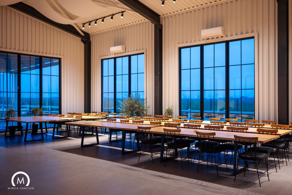Contemporary conference room with multiple tables and chairs overlooking city views through floor-to-ceiling windows.
