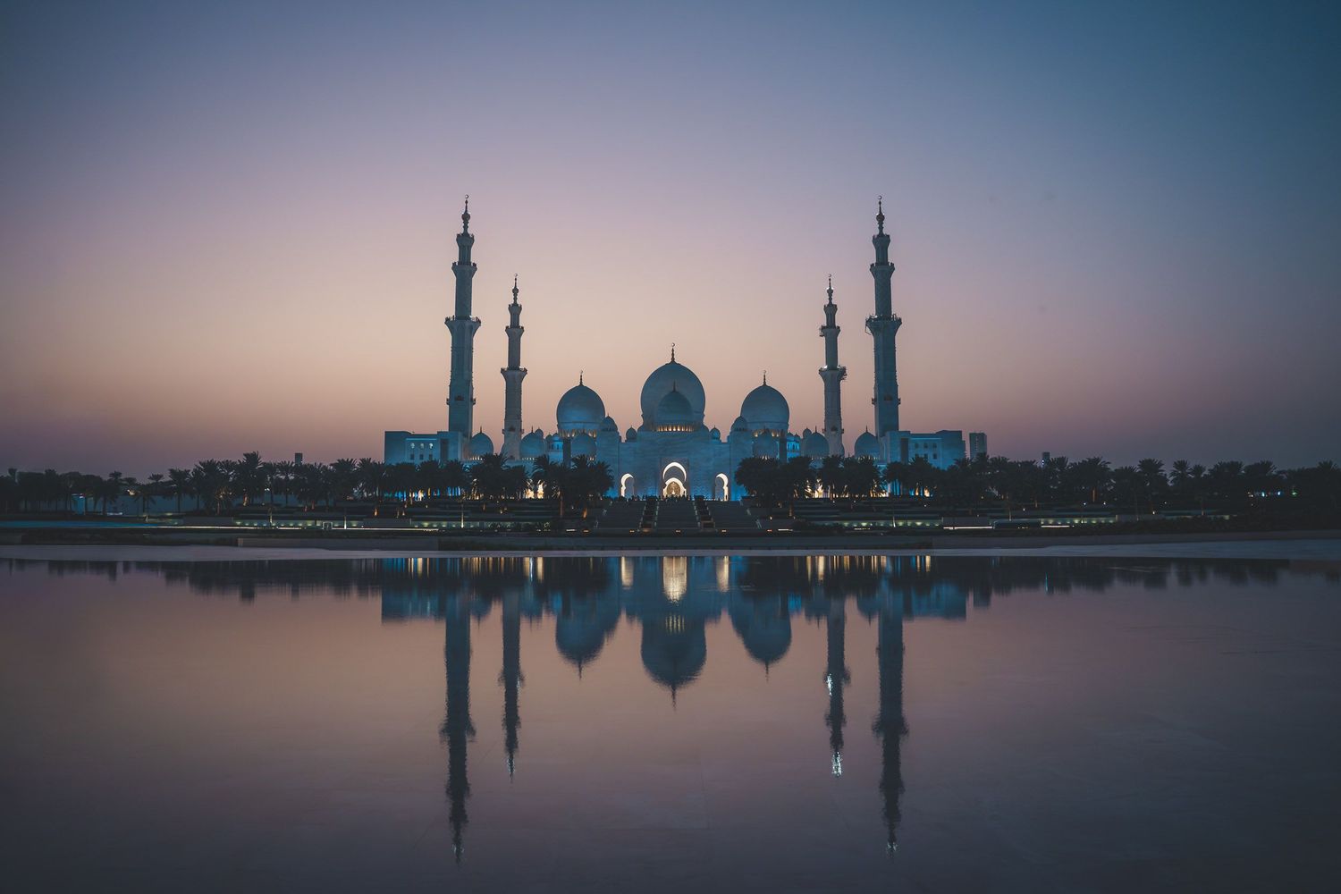 Sheikh Zayed Grand Mosque reflecting off the water during sunset.