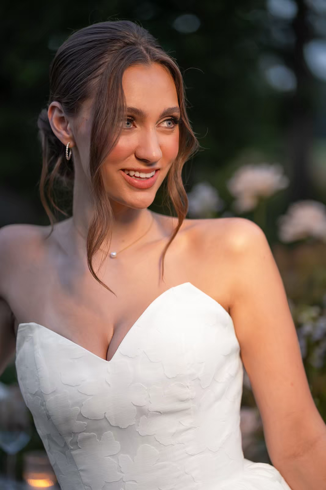 A close-up shots showing details of a bride in her white strapless wedding dress with sweetheart neckline in natural lighting.
