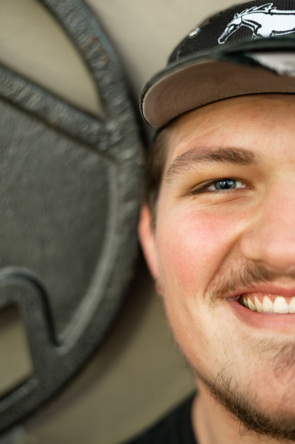 Close-up shot of a person smiling while standing near exercise equipment in a gym setting.