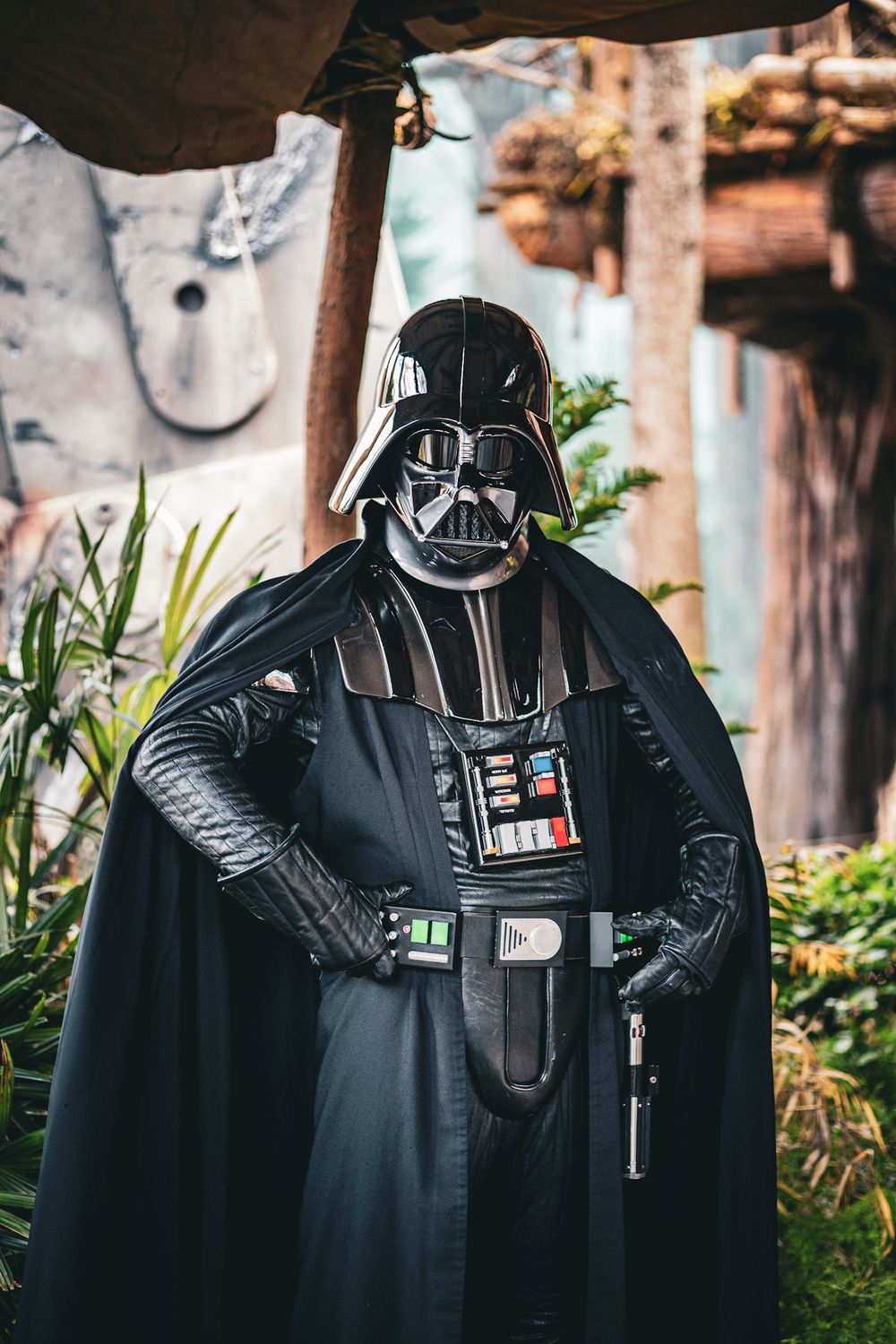 A Darth Vader costume displayed in a garden setting with green plants and foliage in the background.