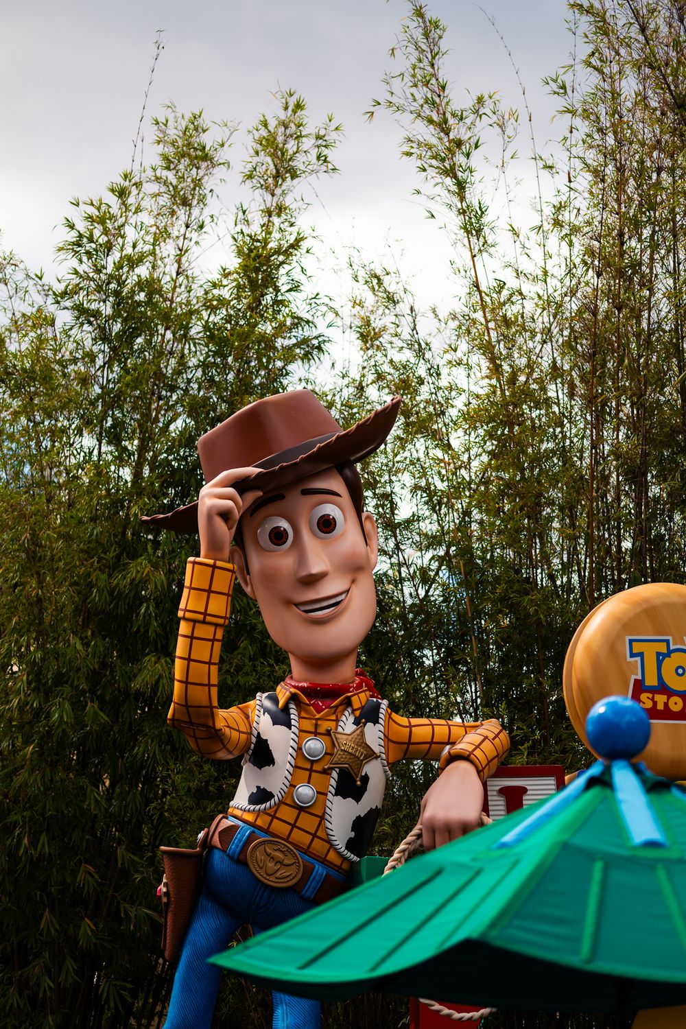 Large Woody character figure from Toy Story displayed outdoors against bamboo backdrop.