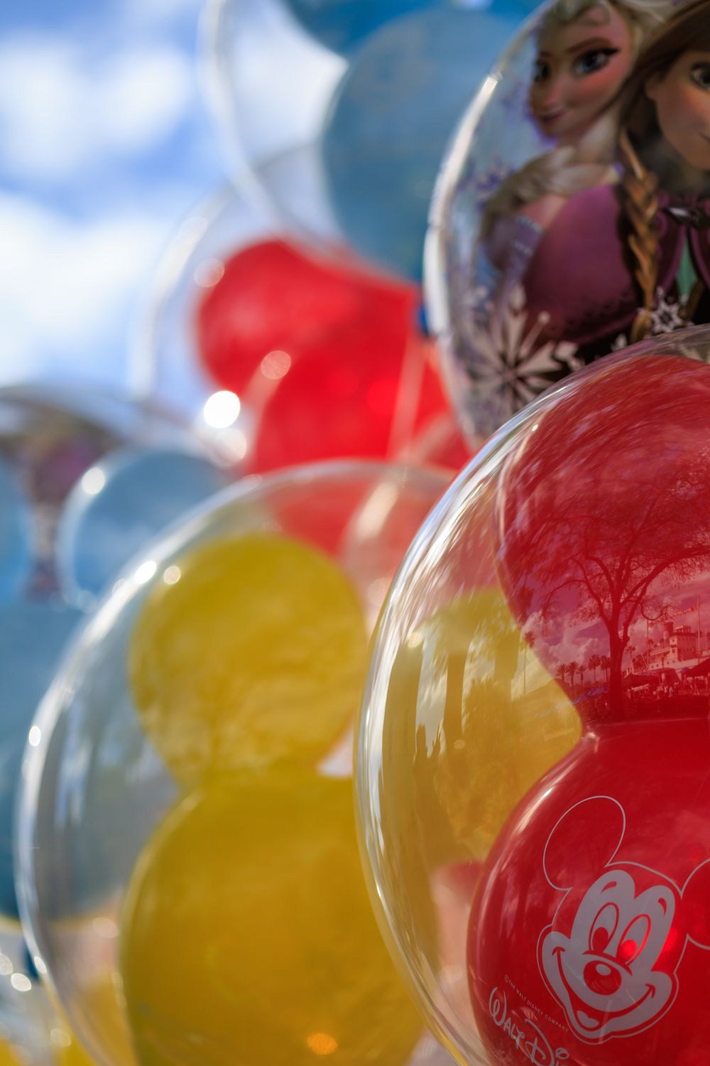 Colorful Mickey Mouse themed helium balloons in red, yellow and blue colors displayed at a Disney event.