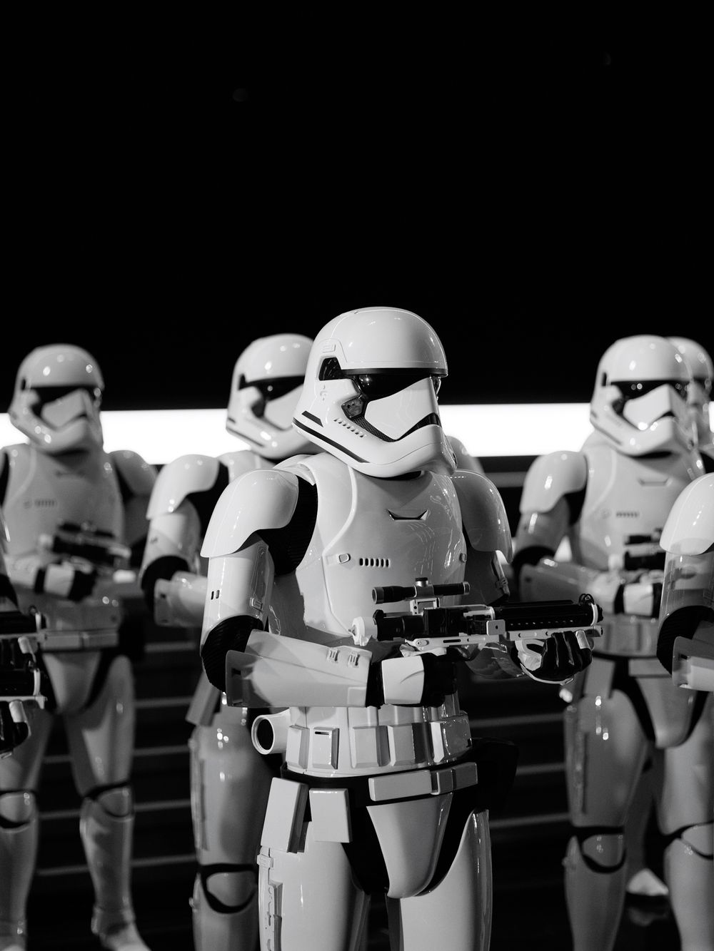 A line of Star Wars Stormtrooper figures in white armor standing in formation against a dark background.