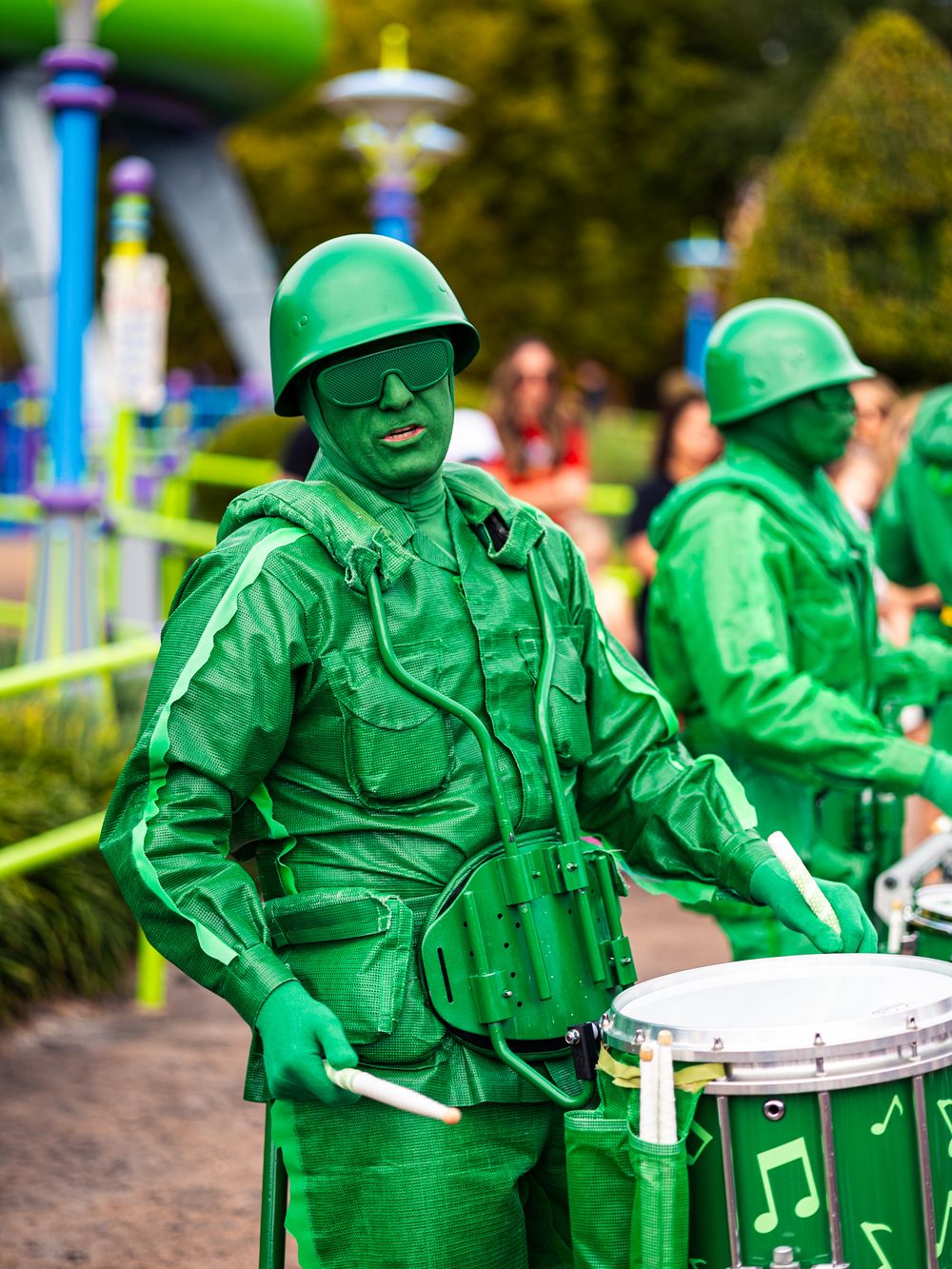 Green toy soldiers playing drums in formation at theme park display.