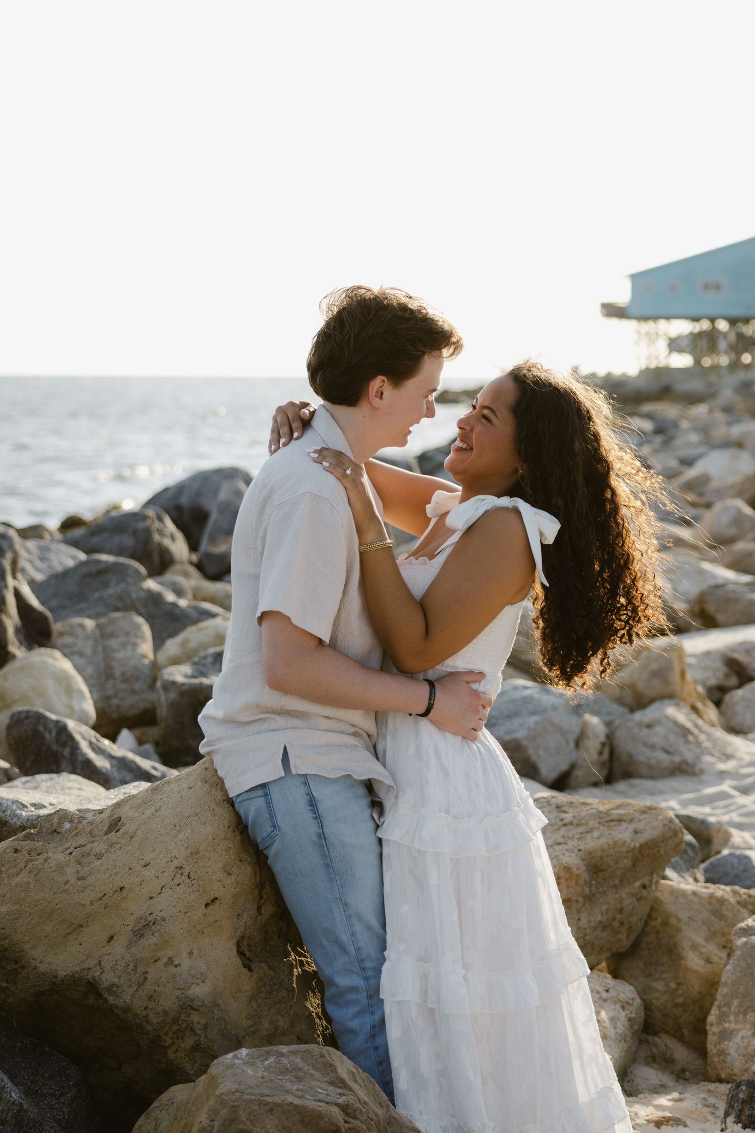 Evening golden hour engagement photos on a rocky coastal beach in Florida.