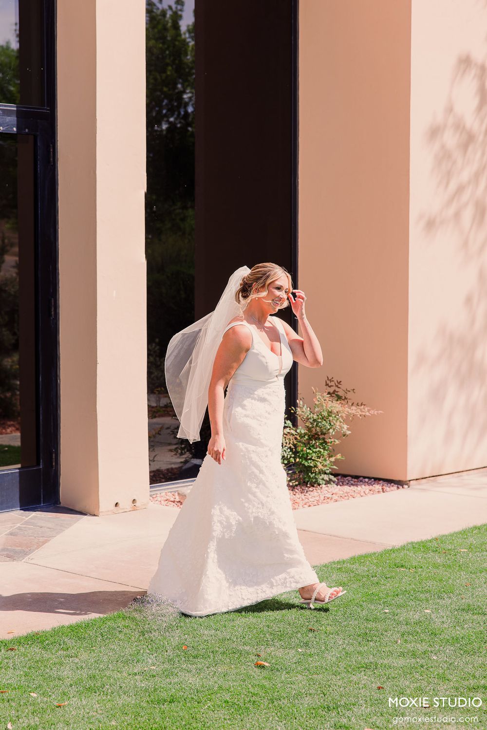 A sequence of photos showing a bride in a white dress twirling playfully on a grassy lawn near columns.