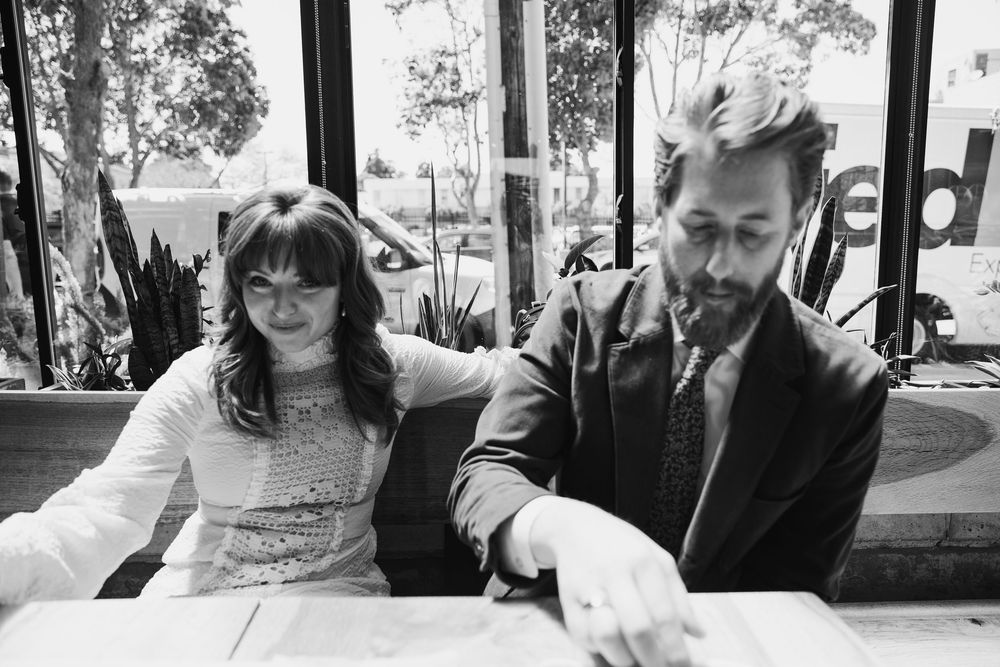 Black and white photo of couple seated at table by window.
