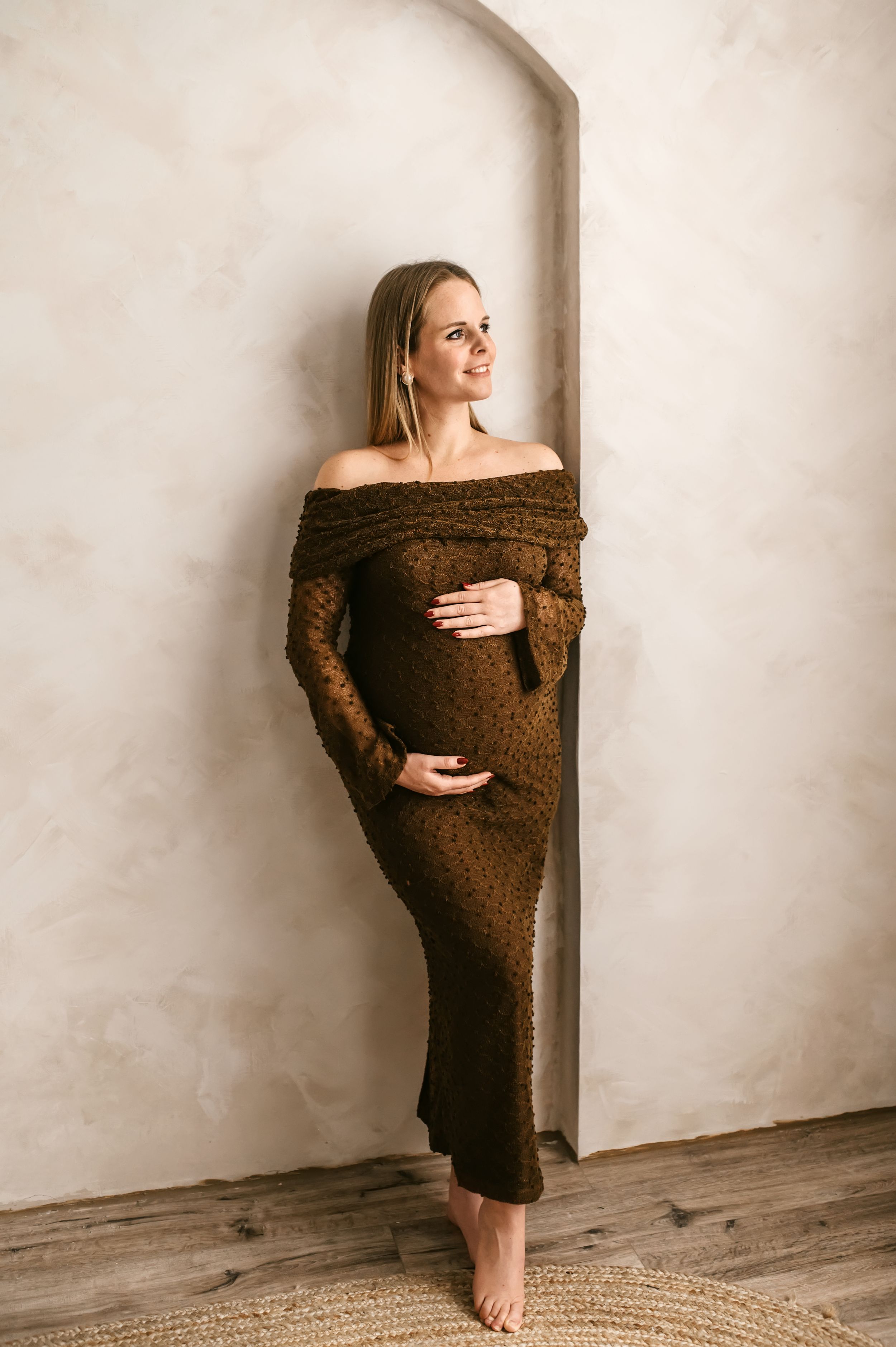 A series of artistic maternity portraits showing a woman in a brown sweater dress against a light wall.