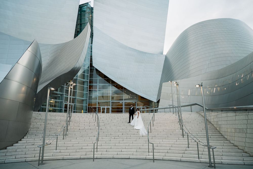 Modern architectural building with curved metallic surfaces and white stone steps leading to entrance at Walt Disney Concert Hall.