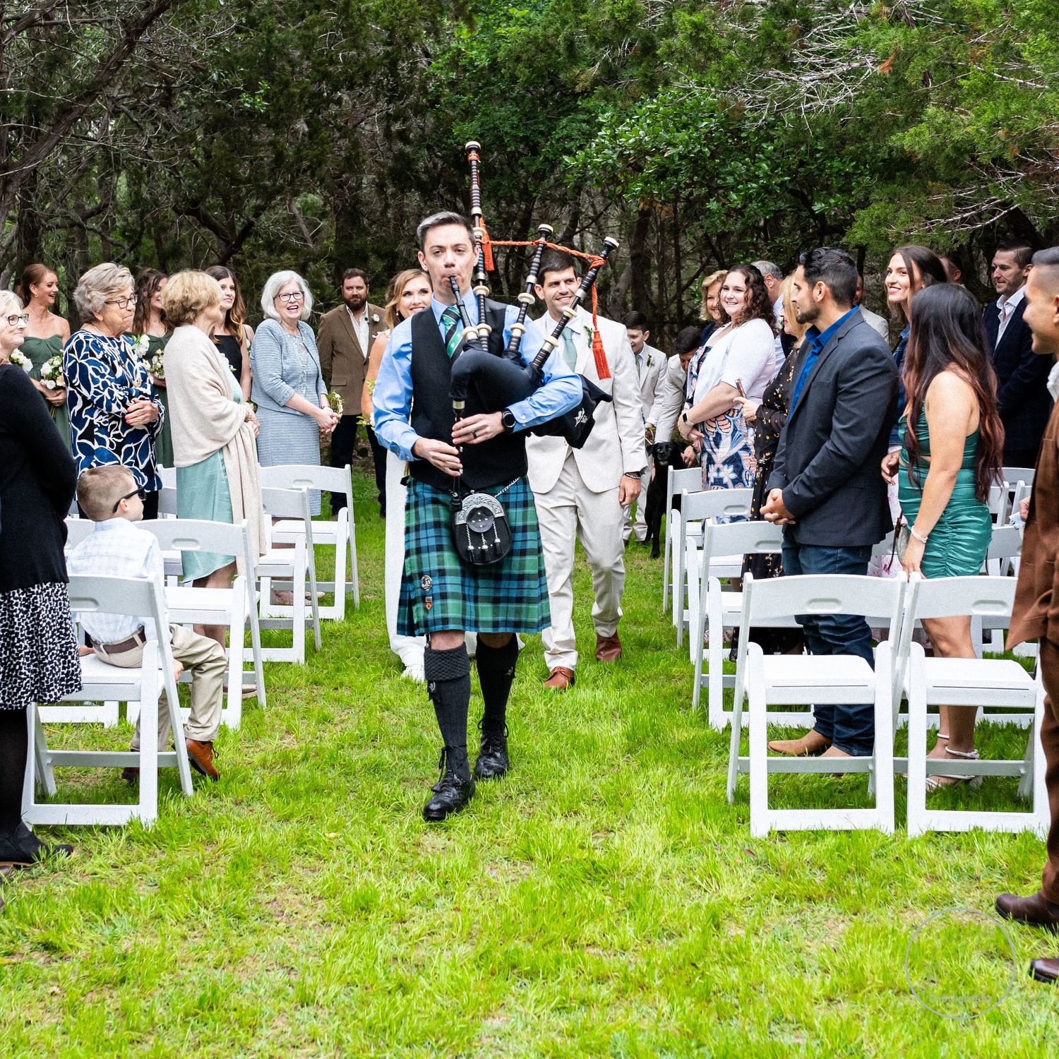 Wedding photo of bagpiper leading bride and groom down aisle