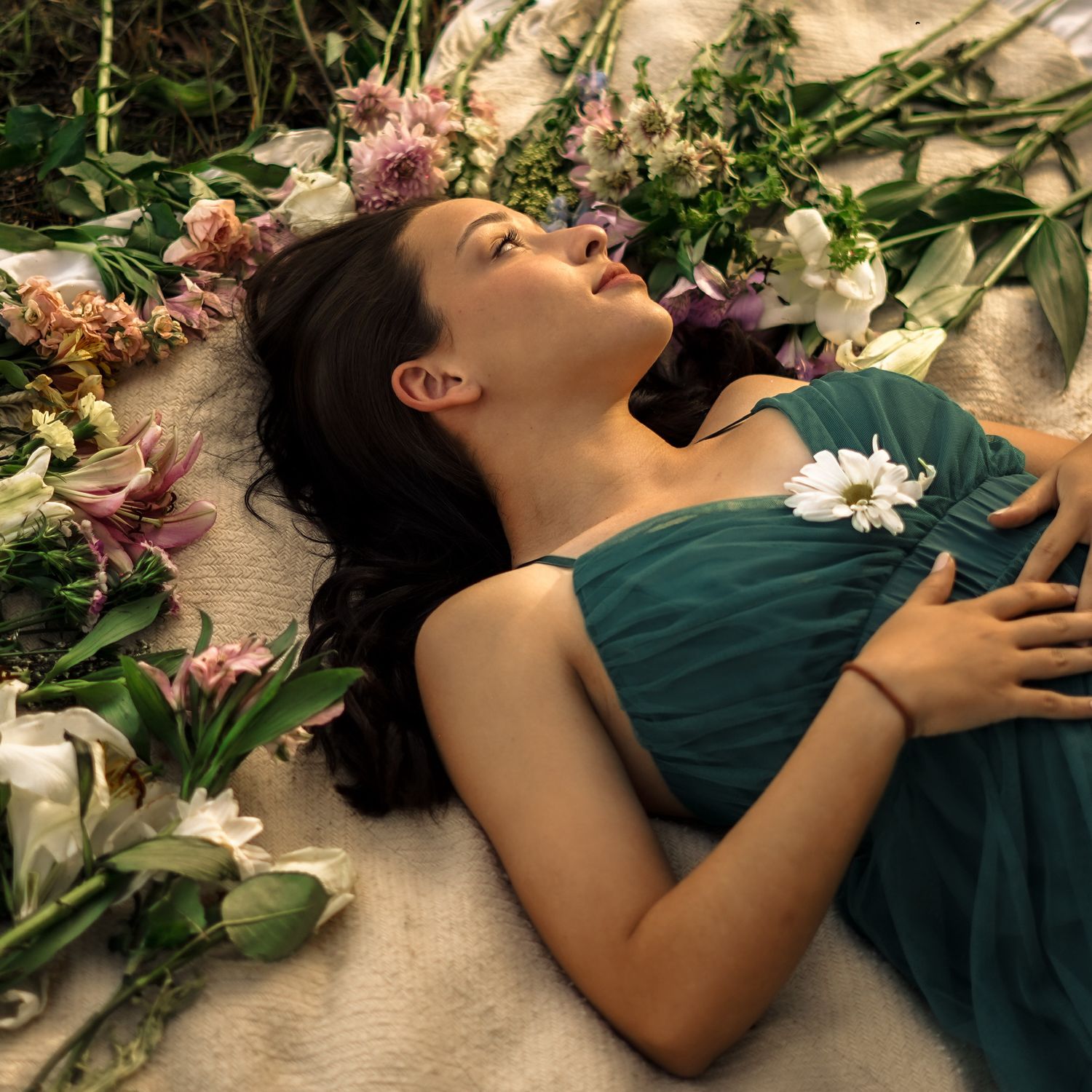 Signature senior session, editorial pose with flowers around the models head while she lays on the ground. Candid-feel styled posing