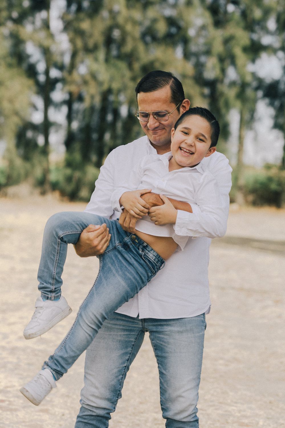 A heartwarming moment between two people in matching white sweaters and jeans, playfully embracing outdoors.