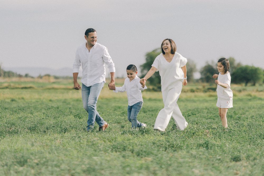 Light and airy photo of a family running together joyfully through a lush green meadow.