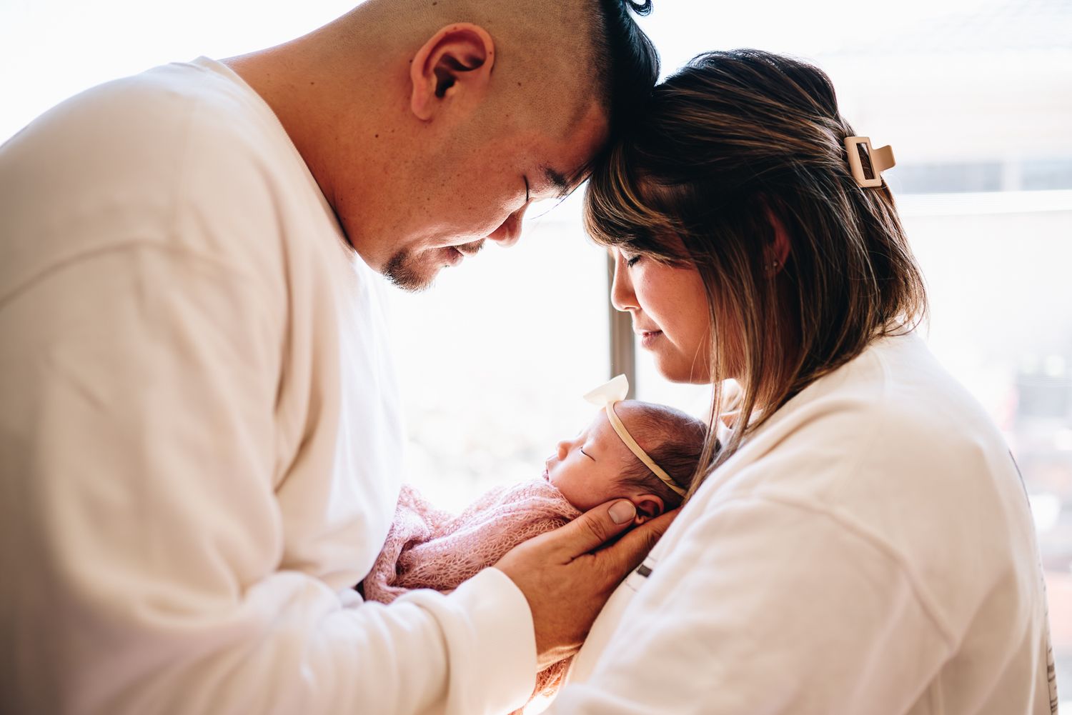 A tender moment between parent and child silhouetted against a bright window at home taken by a Melbourne newborn photographer