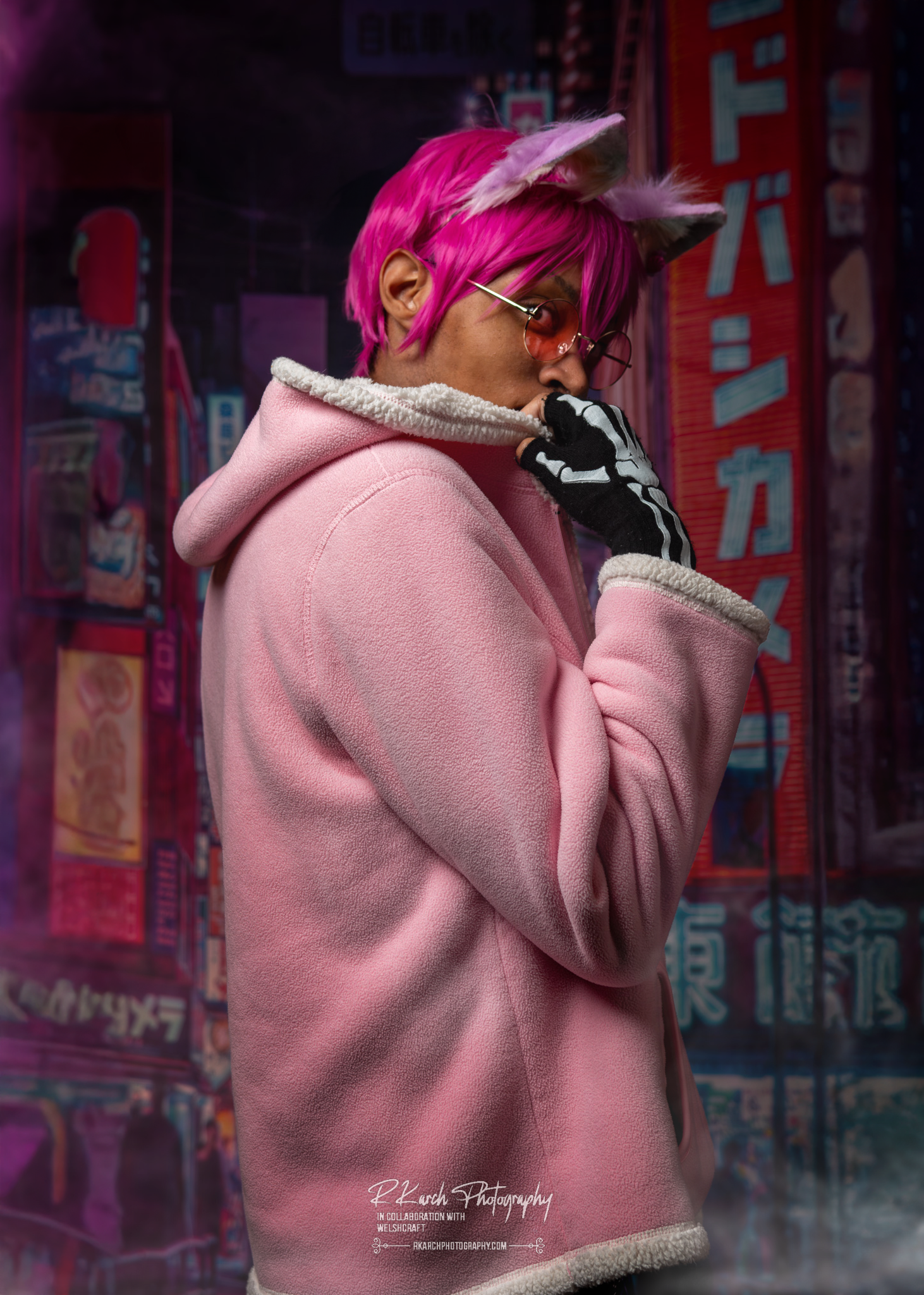 Cosplay portrait featuring pink hair and a cozy pink hoodie against neon city backdrop.