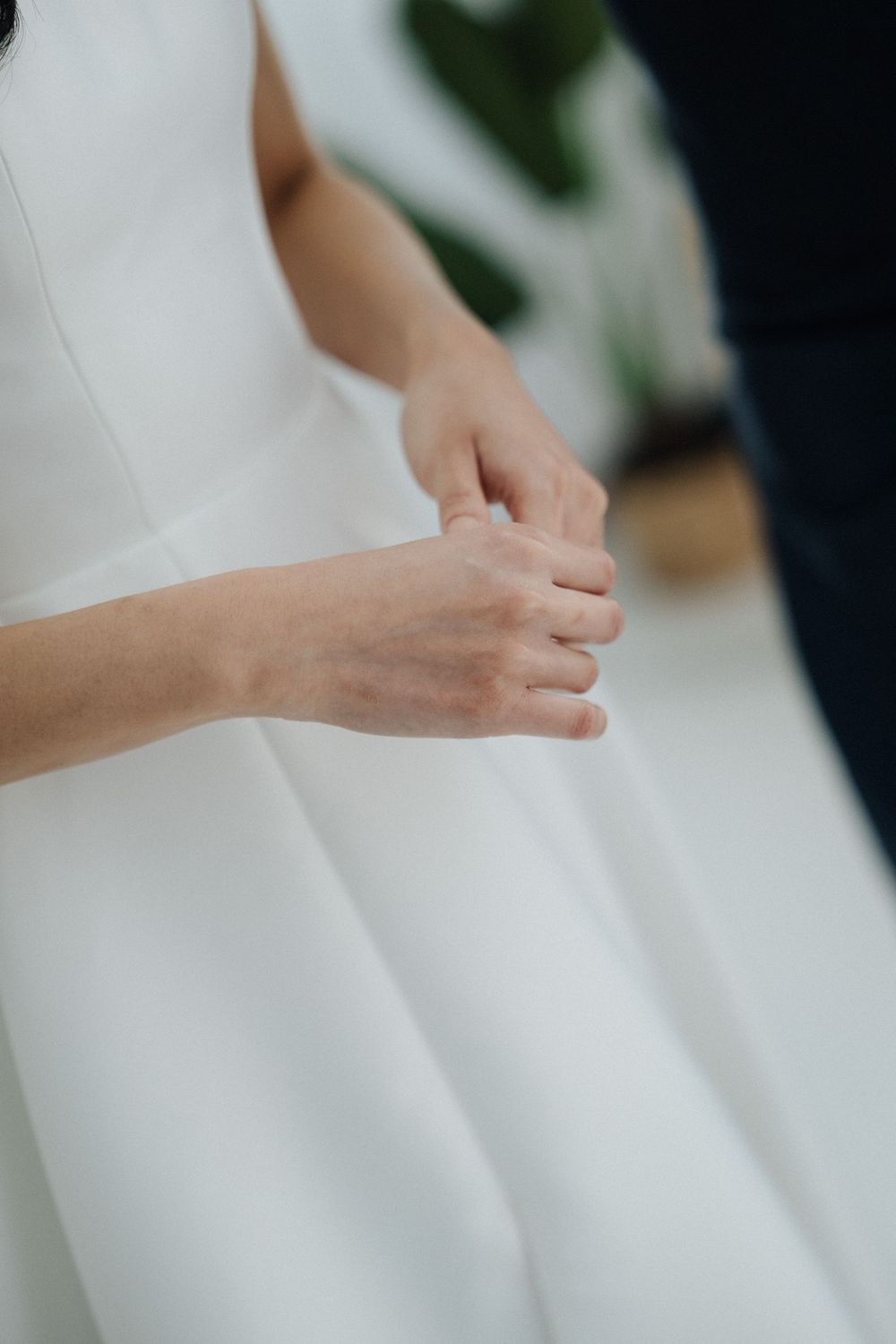 Bride and groom holding hands gently during wedding ceremony, bride wearing elegant white dress.