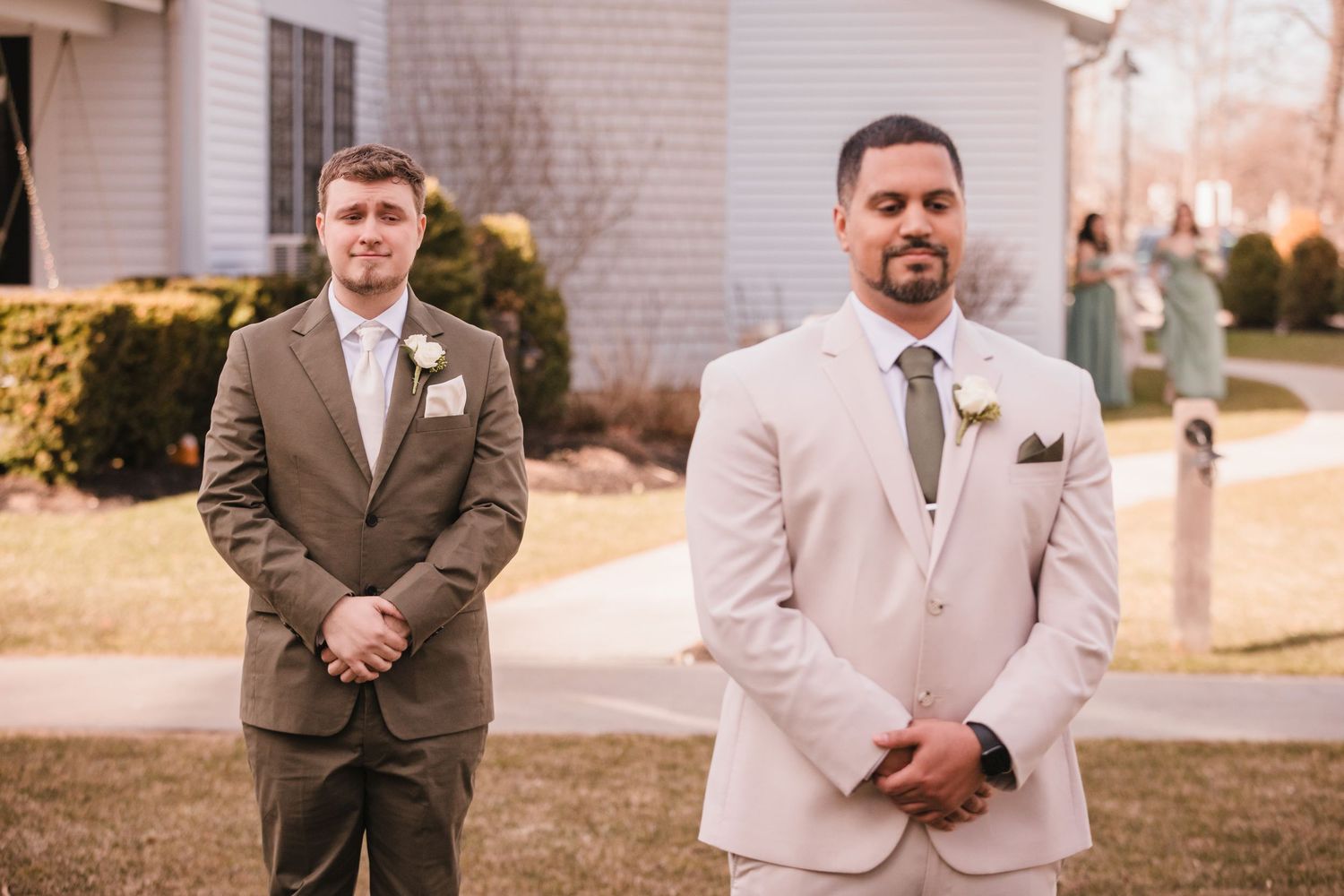 Grooms standing apart before ceremony at Briar Barn Inn wedding Massachusetts with wedding party in background