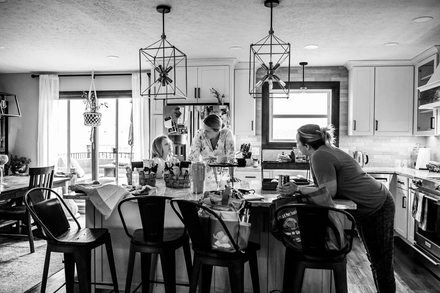Black and white photo of a modern kitchen with pendant lights and bar seating during a home birth