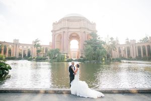 Bride and groom embracing in front of the Palace of Fine Arts lagoon in San Francisco on their wedding day.