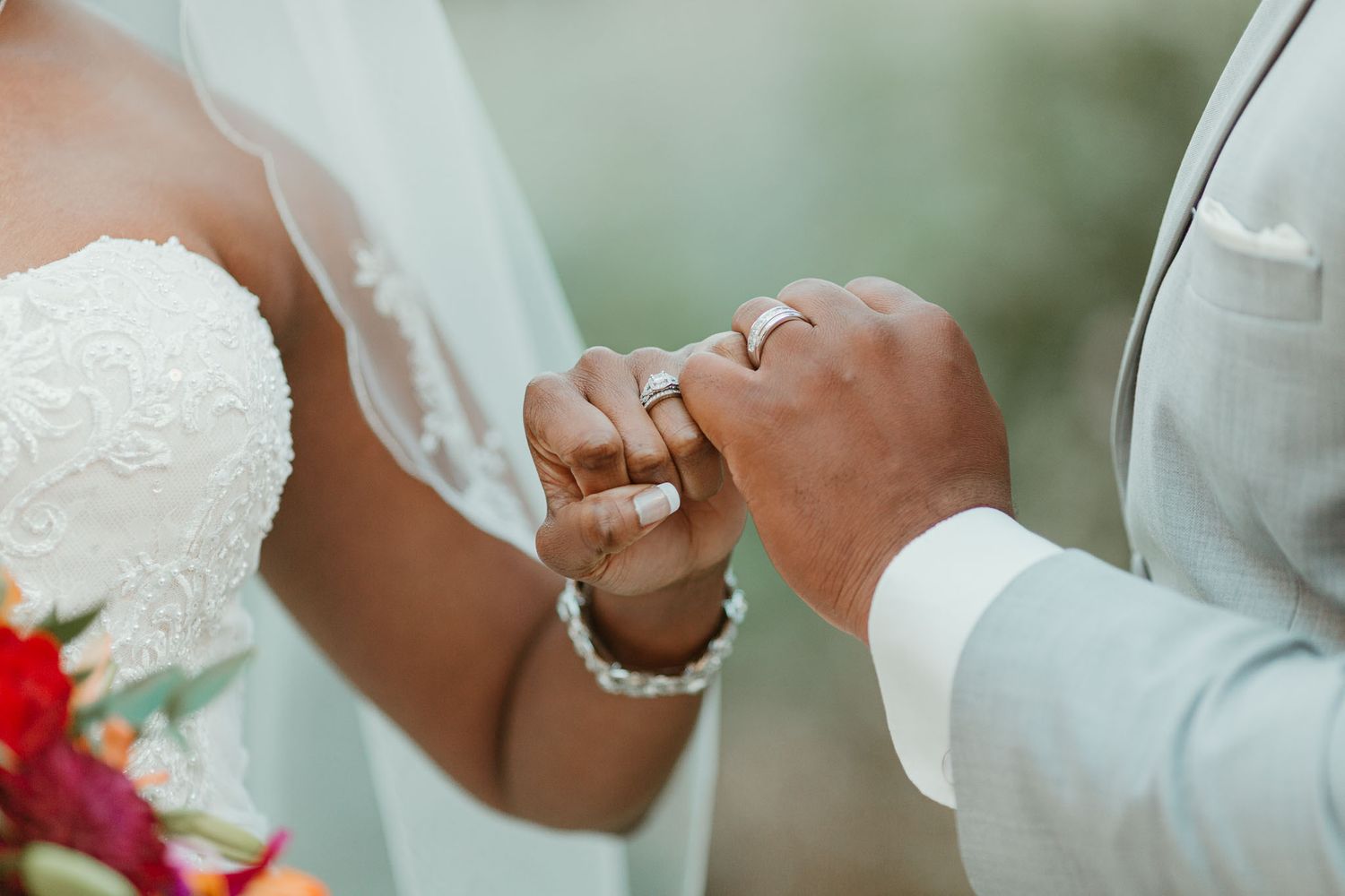 Close-up of bride and groom exchanging rings during wedding ceremony with bridal bouquet.