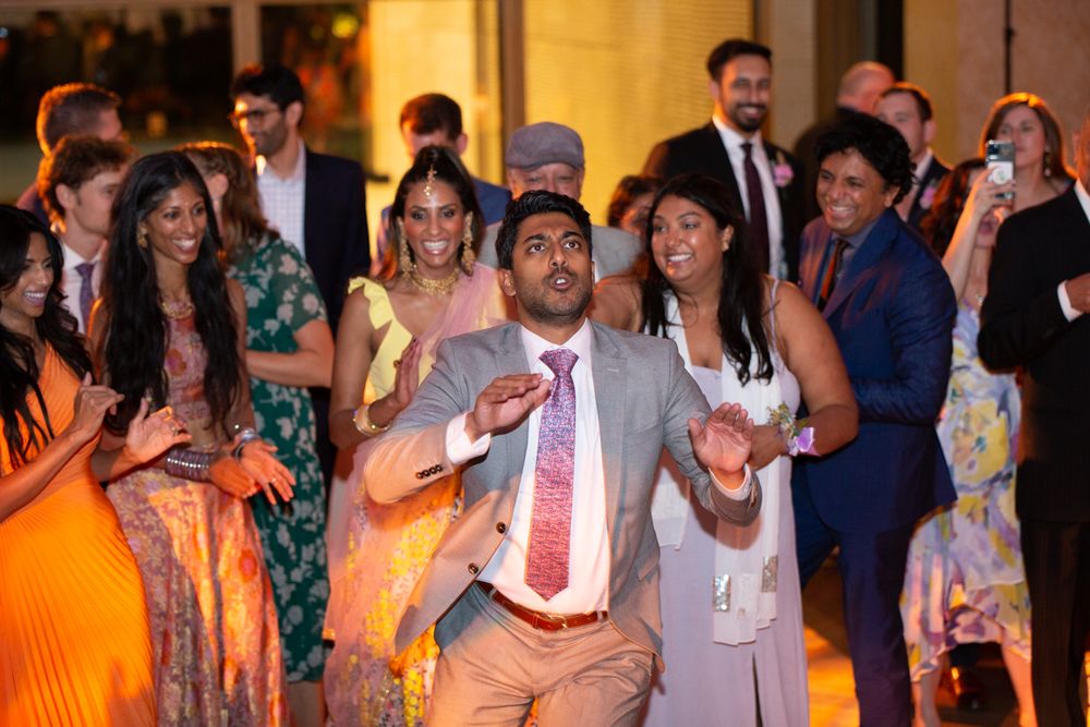 Guests dancing and celebrating joyfully at a colorful Indian wedding reception party.