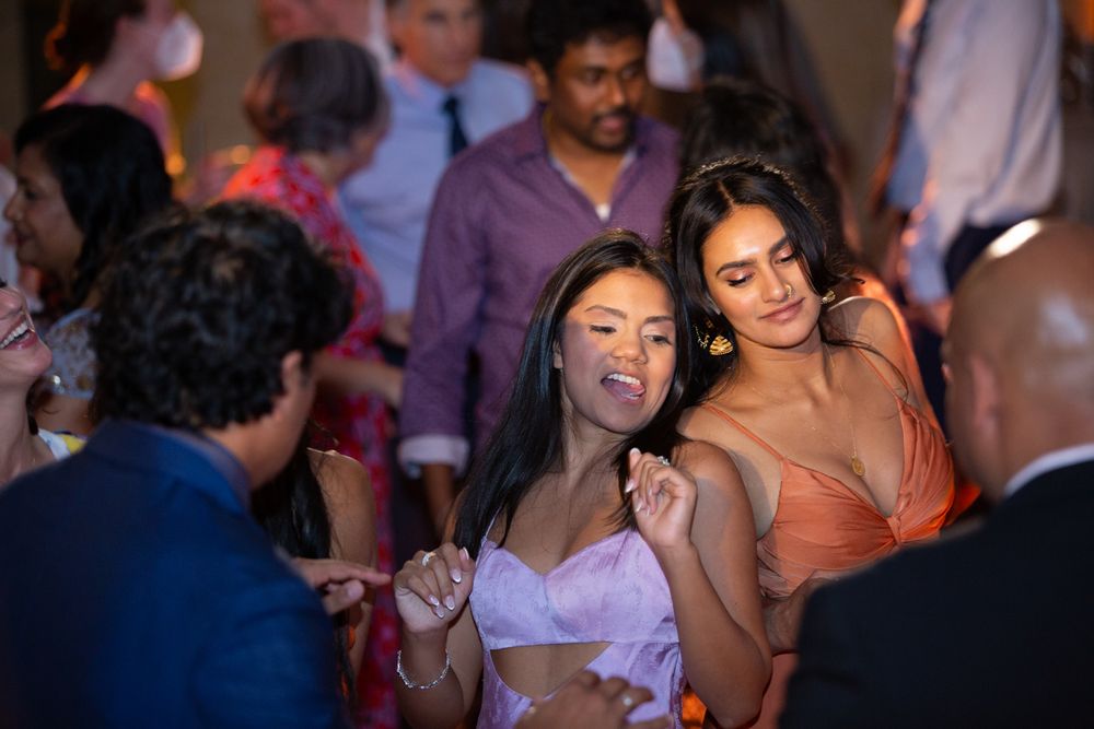 Two women dance together energetically on the dance floor at a festive wedding reception.