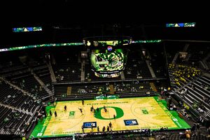 Aerial view of Matthew Knight Arena with Oregon Ducks basketball court and large overhead scoreboard lit up.