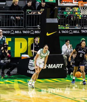 Oregon Ducks women's basketball player dribbles upcourt against Washington Huskies at Matthew Knight Arena.