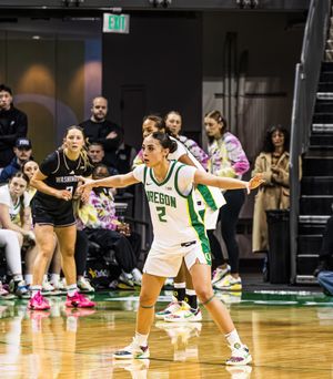 Oregon Ducks player #2 defends against Washington Huskies in women's college basketball game.