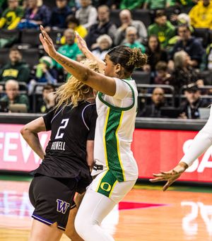Oregon Ducks women's basketball player defends against Washington Huskies number 2 during an intense college game.