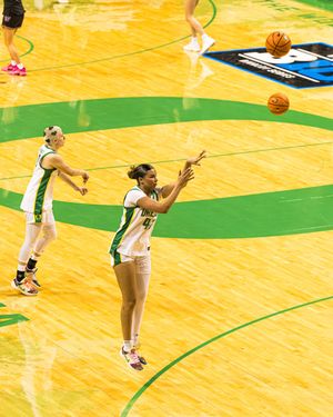 Oregon Ducks women's basketball player passes ball during NCAA tournament game on green court.