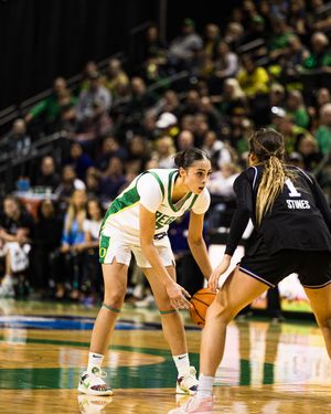 Oregon Ducks women's basketball player dribbles against a defender wearing number 1 during a college game.