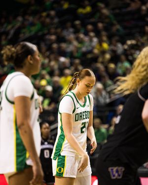 Oregon Ducks women's basketball player wearing jersey number 21 walks on court during game against Washington Huskies.