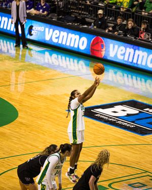 Oregon Ducks player tips off a basketball during a Big Ten women's college basketball game at a Venmo-sponsored arena.
