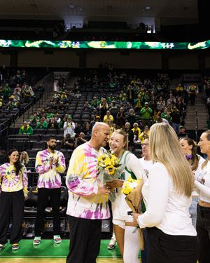 Oregon Ducks women's basketball player receives flowers from family during senior day ceremony at Matthew Knight Arena.