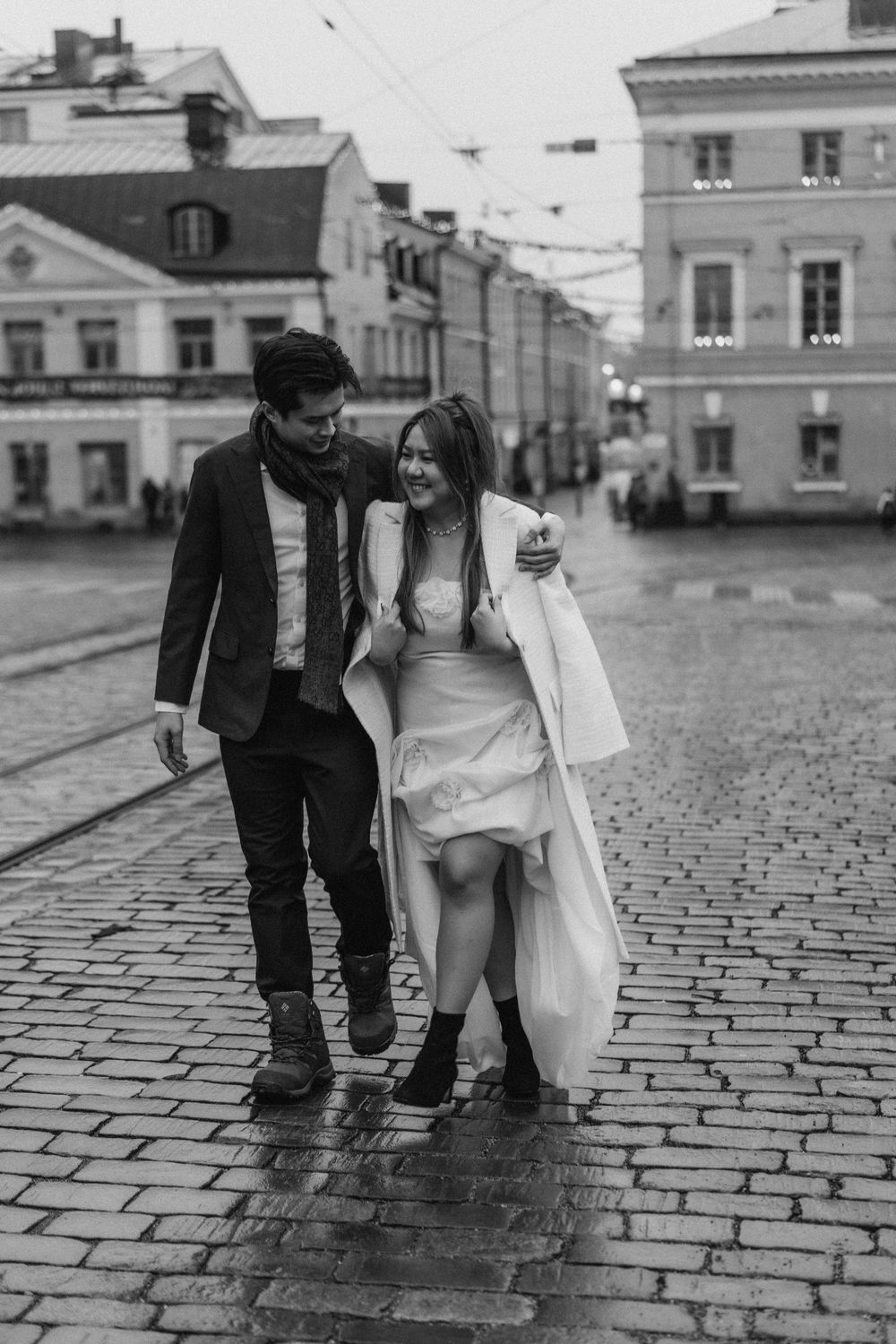 Black and white engagement photo of a couple walking together through Senate Square in Helsinki