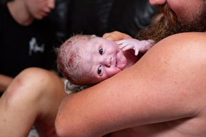 Father cradles his newborn baby skin-to-skin shortly after delivery.