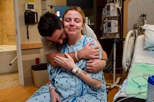 Tender moment of a man embracing a woman in a hospital gown in a maternity ward room.