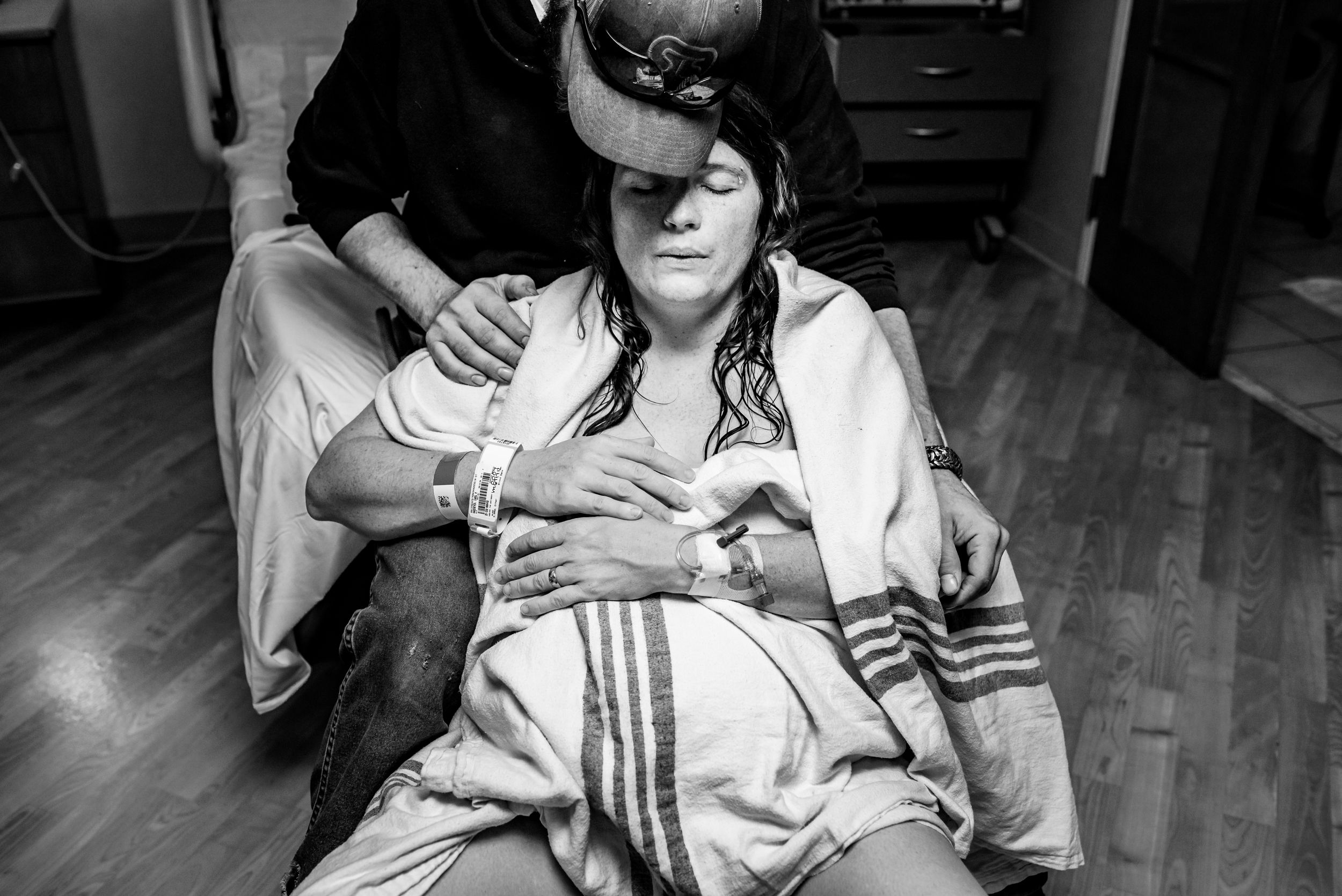 Supportive partner comforting a pregnant woman during labor in a hospital room.