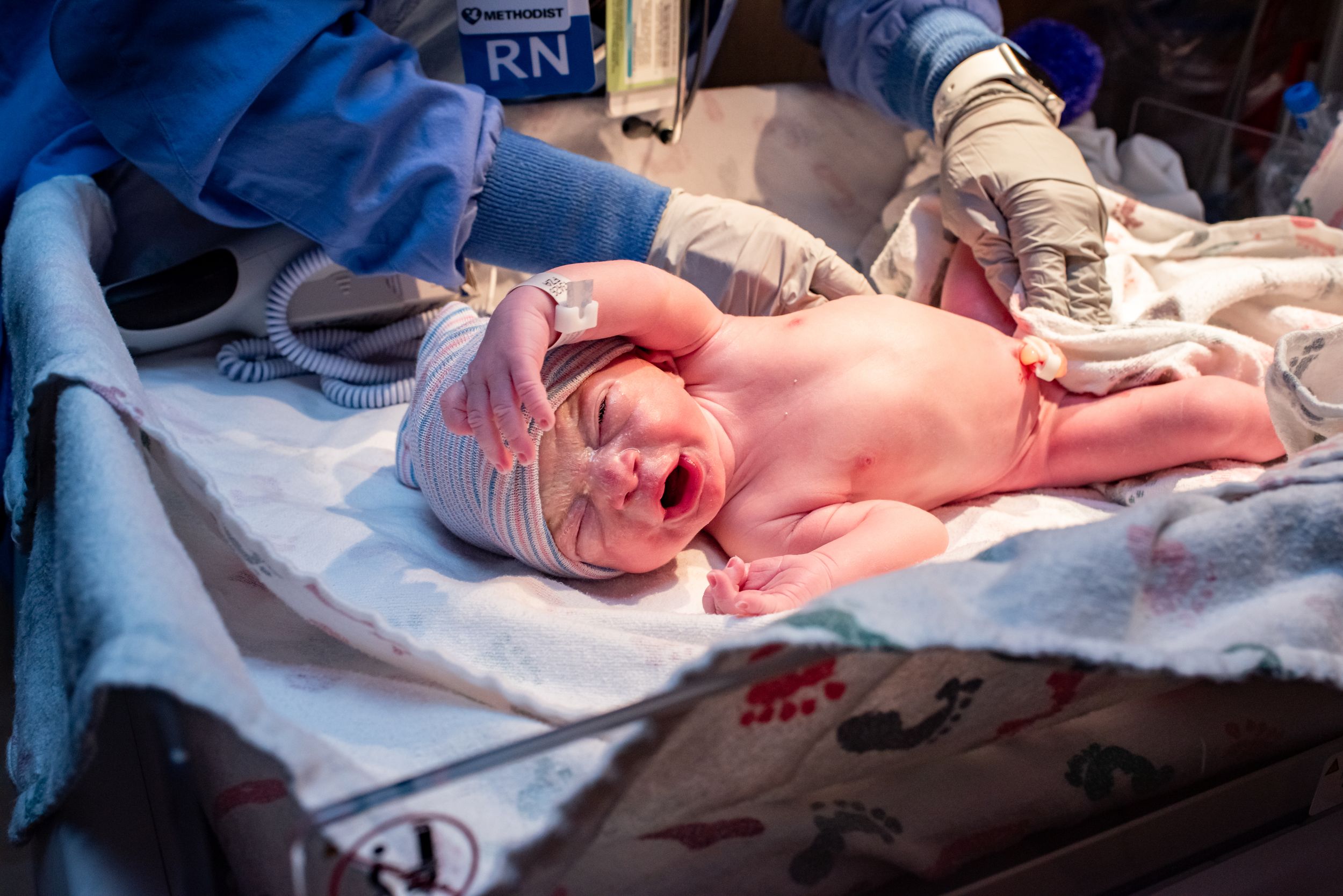 Newborn baby crying moments after birth in a hospital delivery room.