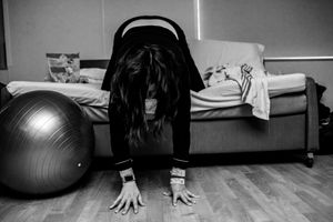 Black and white photo of woman in labor leaning over a birthing ball.