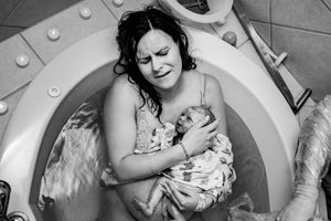 Emotional black and white photo of a mother holding her newborn baby after a water birth in a hospital tub.