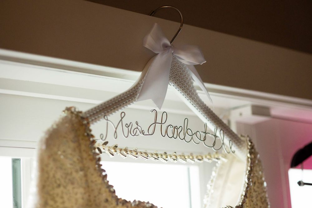 Custom wire wedding dress hanger spelling Mrs. Hardbattle adorned with white ribbon bow.